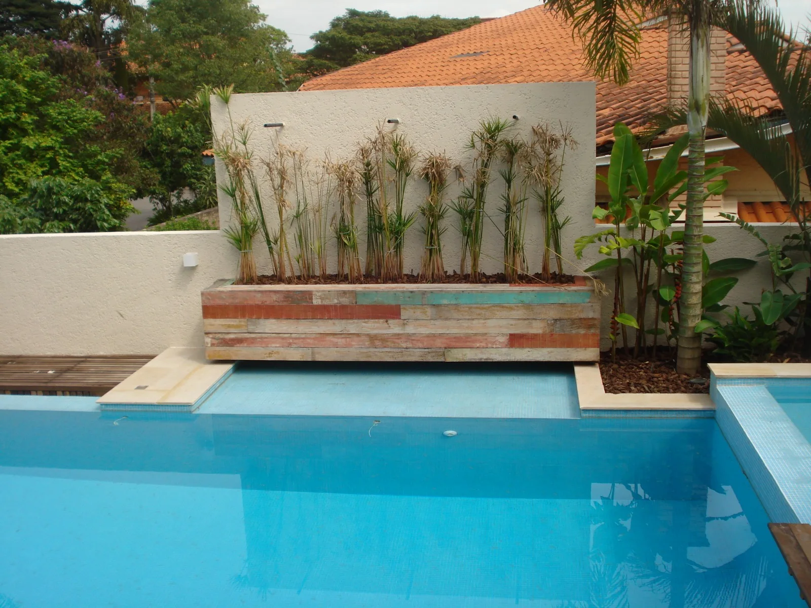 Piscina com parede de água e vegetação